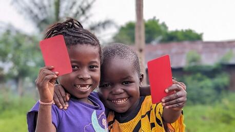 In Kwango Province, Democratic Republic of the Congo (DRC), 5-year-olds Makiese, left, and Madinu brandish red cards after receiving their polio vaccinations in 2023.