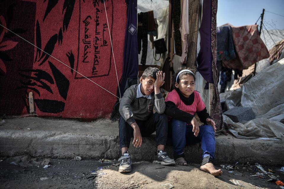 Muhammad, 11, and his sister Hala, 12, sit outside their tent in Rafah, southern Gaza.
